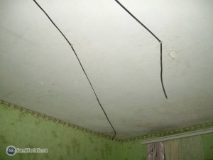 Прокладка кабеля по потолку, кабель справа - под люстру, слева - входит в гипсокартонную стену и опускается вниз к розетке.